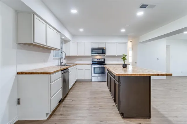 a kitchen with granite countertop a sink dishwasher a stove and white cabinets with wooden floor