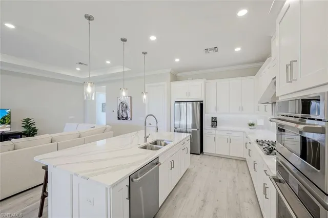 a large kitchen with a large counter top a sink a stove a refrigerator and a center island