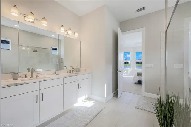 a spacious bathroom with a double vanity sink a mirror and shower