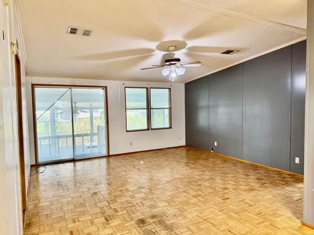 an empty room with windows and ceiling fan