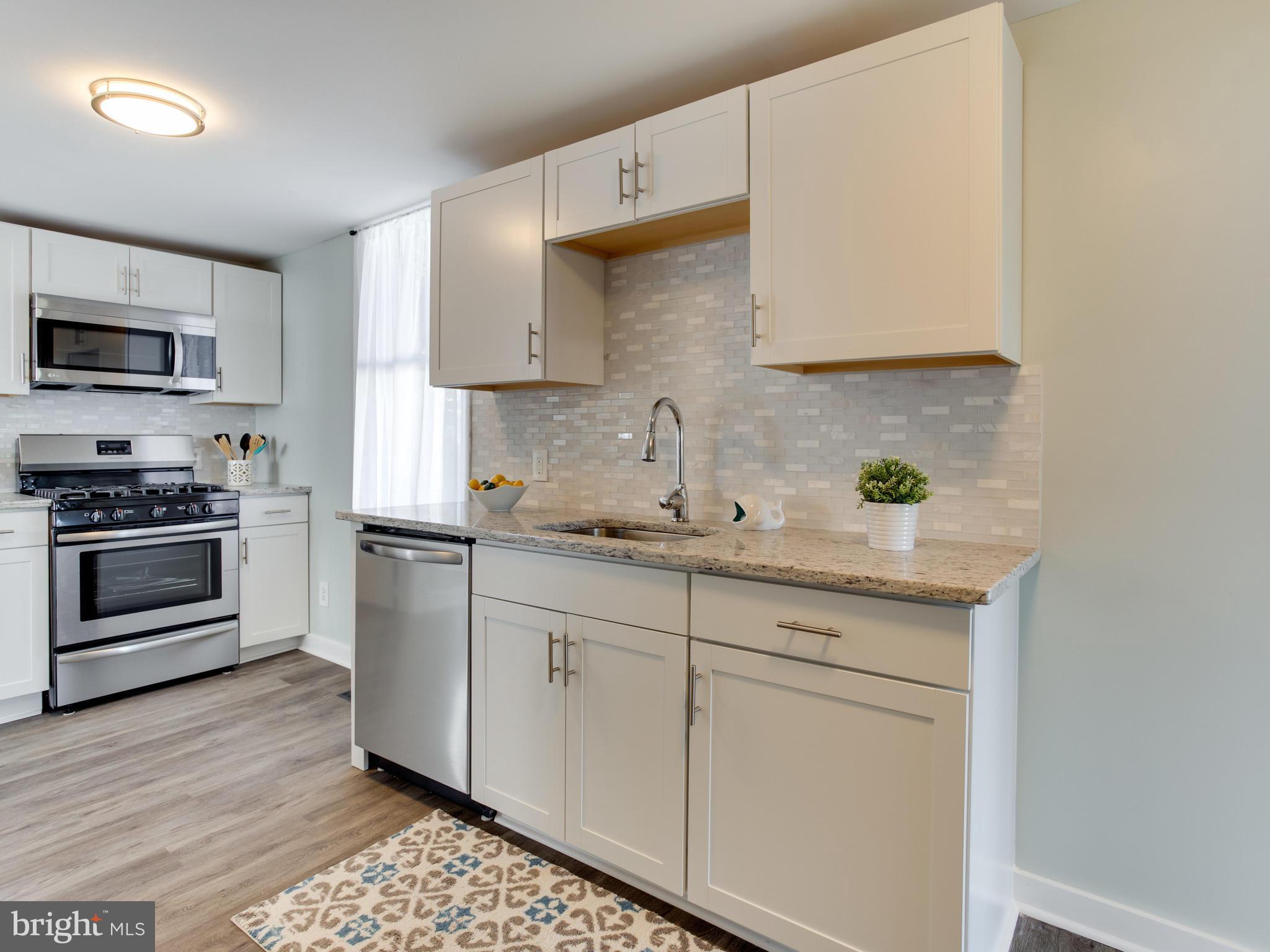 110 West Hilltop Road Baltimore, MD 21225 - Photo 12 of 30 a kitchen with granite countertop a stove a sink and a microwave