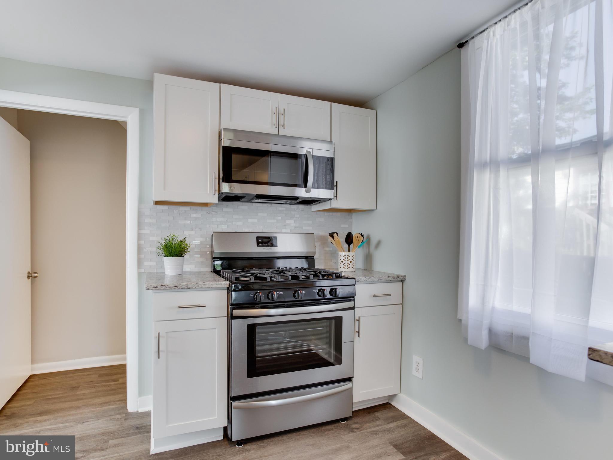 110 West Hilltop Road Baltimore, MD 21225 - Photo 13 of 30 a kitchen with white cabinets and stainless steel appliances