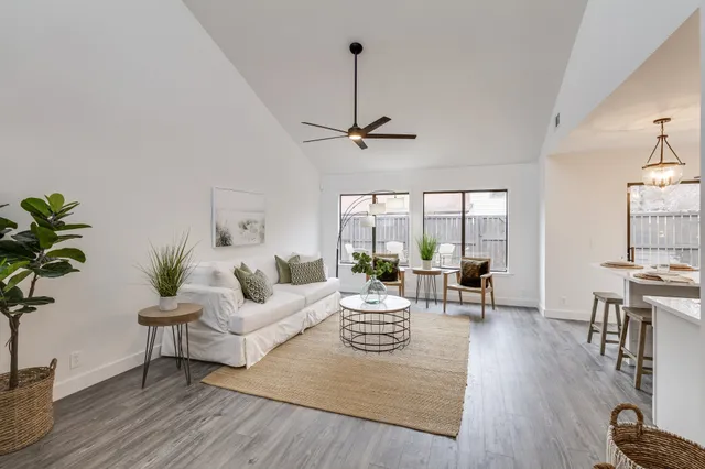a living room with furniture large window and wooden floor