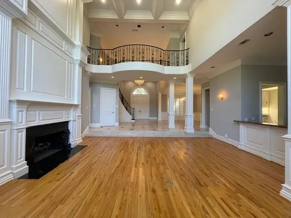 a view of an empty room with wooden floor fireplace and a window
