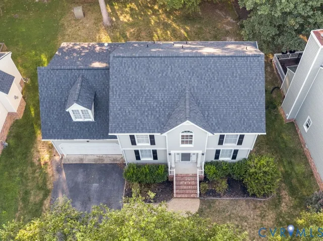 an aerial view of a house with a yard and a large tree