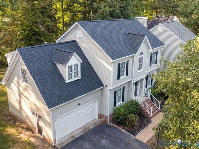 a view of a house with a yard plants and large tree