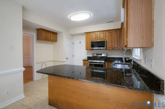 a kitchen with granite countertop a stove top oven a sink a counter space and cabinets
