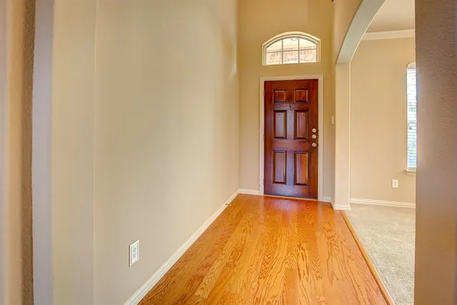 a view of a hallway with wooden floor and a bathroom