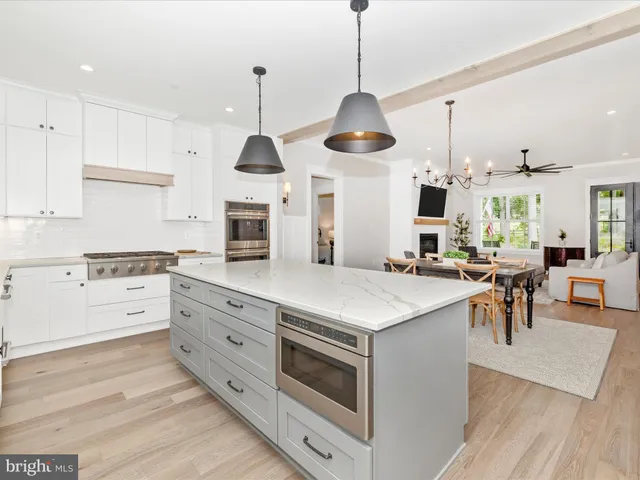 a kitchen with stainless steel appliances kitchen island granite countertop a stove a sink a dining table and chairs with wooden floor