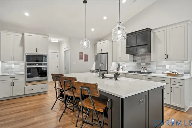 a kitchen with stainless steel appliances a stove a sink a microwave a dining table and chairs