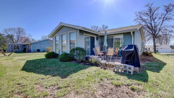 a view of a house with a yard and chairs