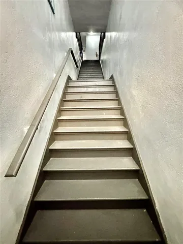 a view of a hallway with wooden floor and a bathroom