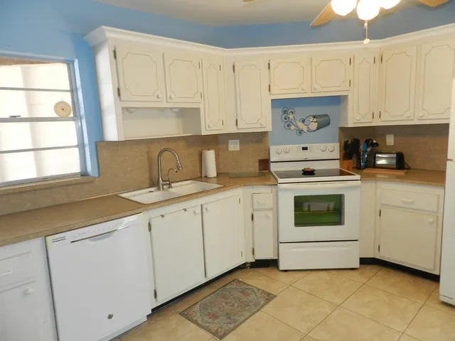 a kitchen with cabinets appliances a sink and a window