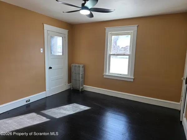 a view of an empty room with a window and wooden floor