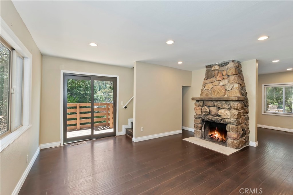 23739 Hillside Drive Crestline, CA 92325 - Photo 11 of 37 an empty room with wooden floor fireplace and windows