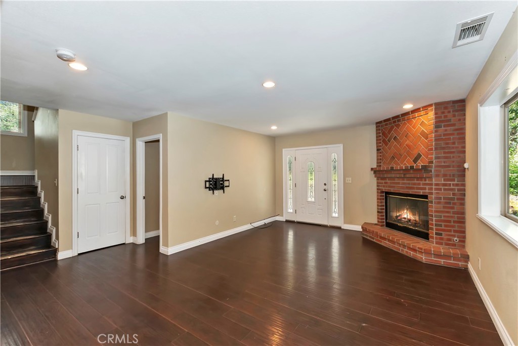 23739 Hillside Drive Crestline, CA 92325 - Photo 5 of 37 an empty room with wooden floor fireplace and windows