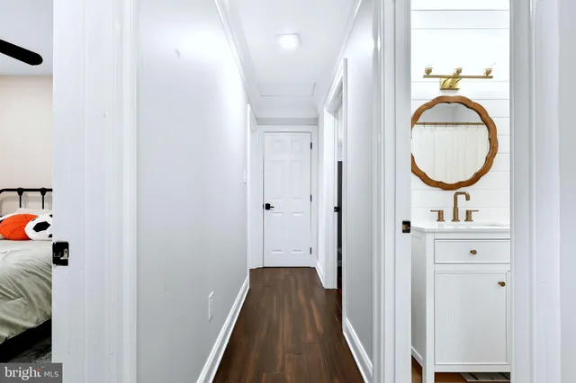 a view of a hallway with wooden floor and bathroom