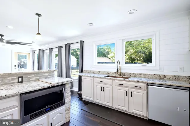 a kitchen with granite countertop stainless steel appliances a stove sink and microwave