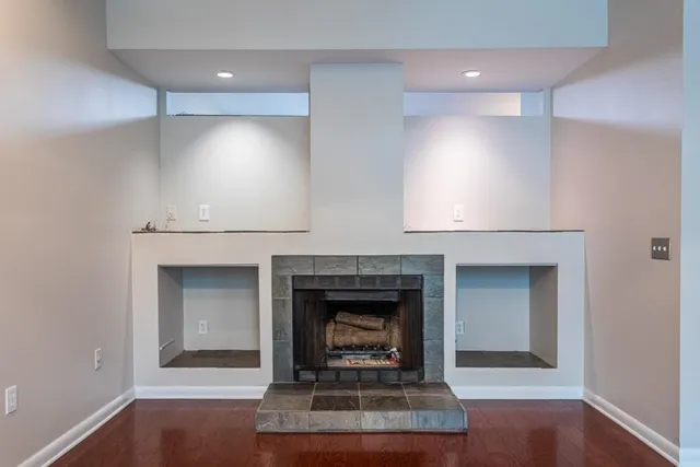 a view of an empty room with wooden floor fireplace and a window