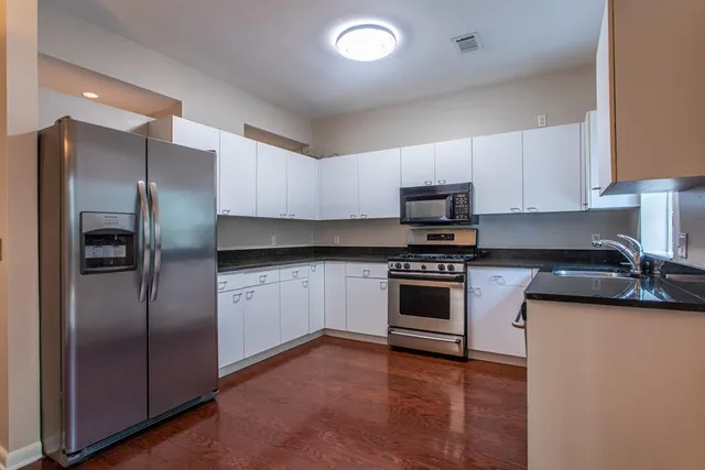 a kitchen with stainless steel appliances granite countertop a refrigerator a stove a sink and a microwave