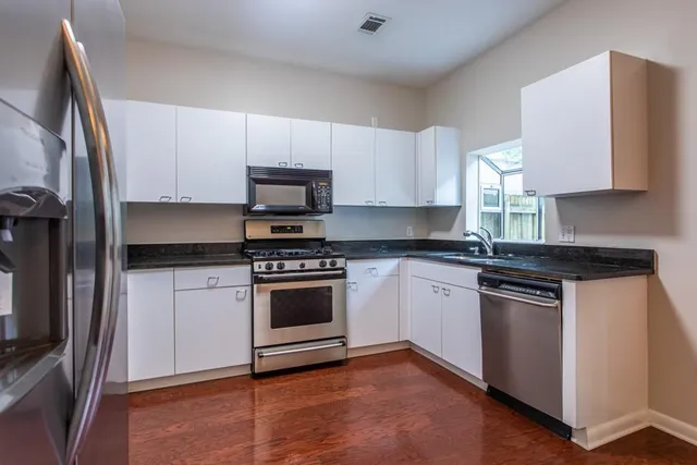 a kitchen with granite countertop a sink and a white wooden cabinets