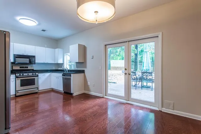 an empty room with wooden floor a ceiling fan and windows