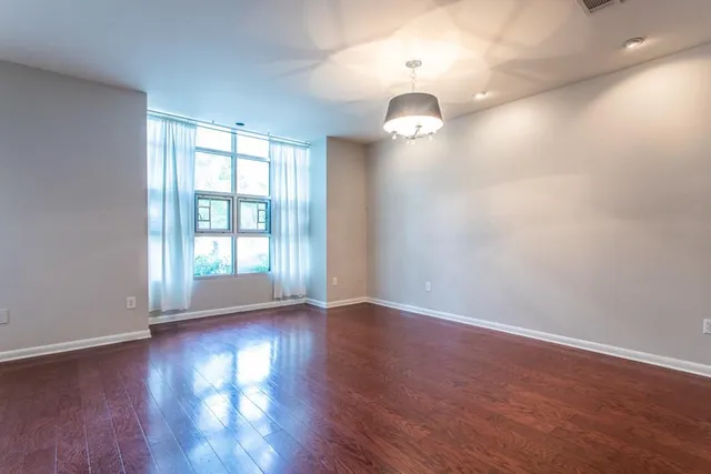 a view of an empty room with wooden floor and a window