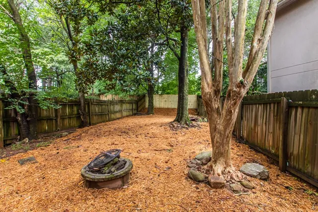 a backyard of a house with large trees and wooden fence
