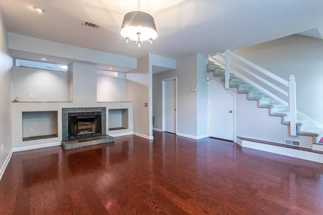 an empty room with wooden floor fireplace and windows