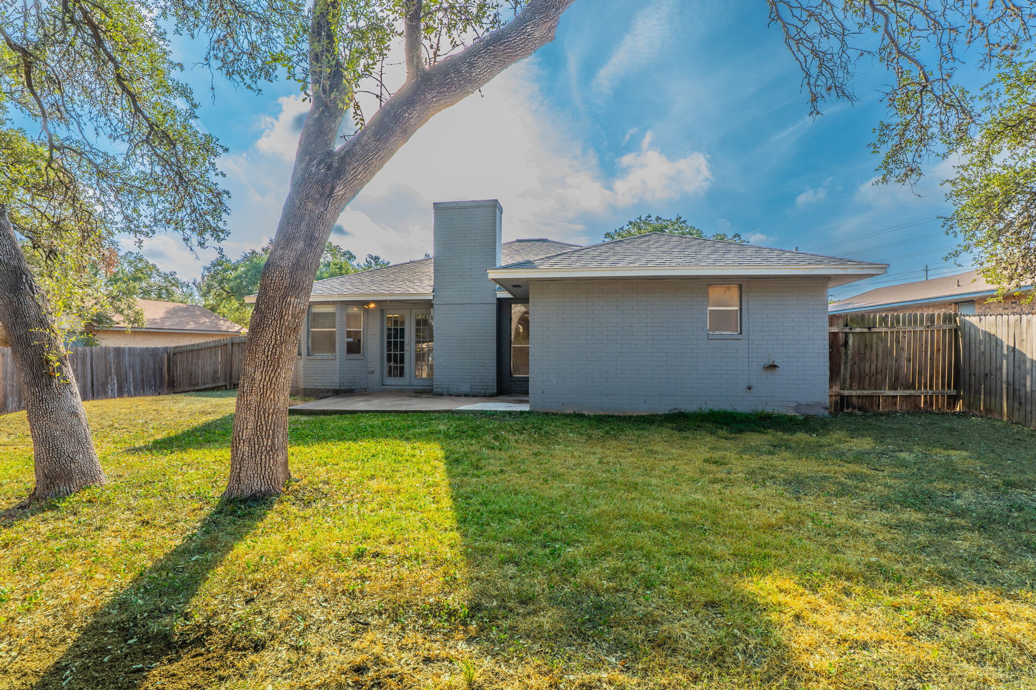 5628 Wagon Train Road Austin, TX 78749 - Photo 26 of 26 Mature shade trees frame the grass lawn and concrete patio behind this brick home.