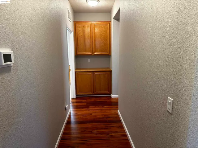 a view of a hallway with wooden floor and a bathroom