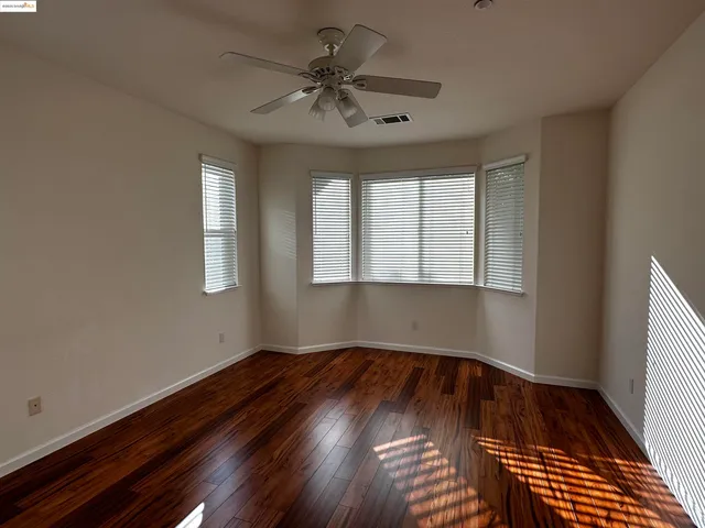 a view of an empty room with window and wooden floor