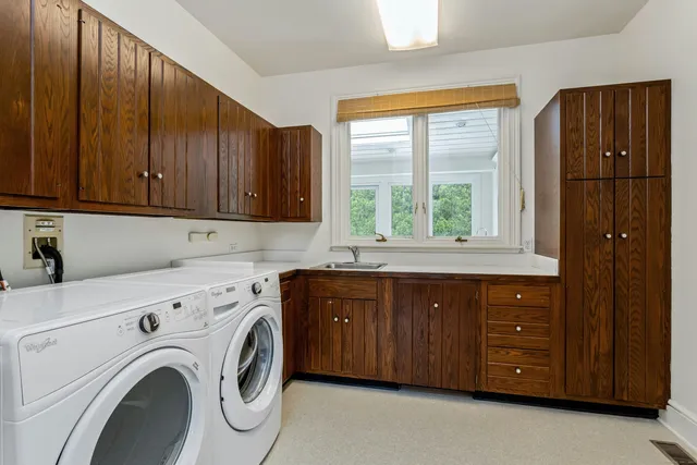 a kitchen with stainless steel appliances granite countertop a sink a washer and dryer next to a window