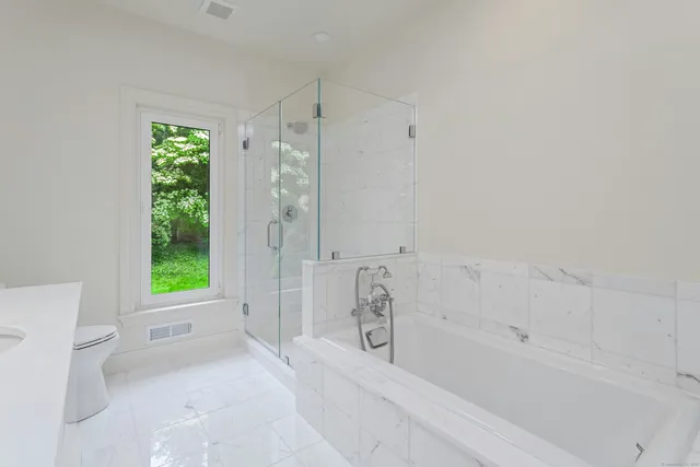 a bathroom with a bathtub shower and toilet