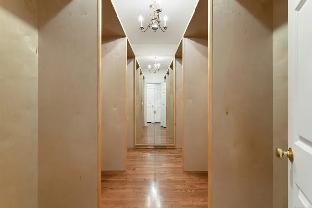 a view of a hallway with wooden floor and chandelier