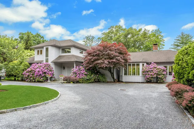a front view of a house with a garden and trees