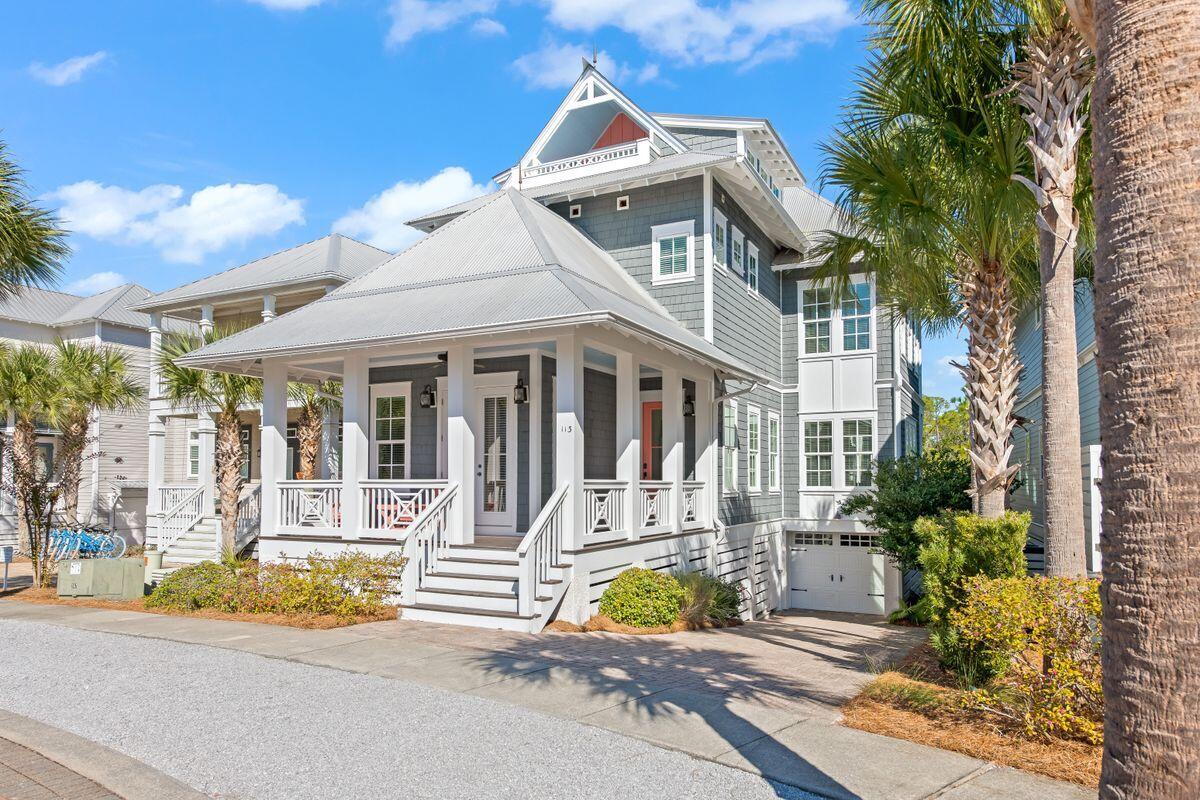 a view of a white house with large windows and palm tree