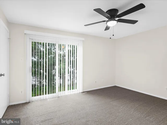 an empty room with a ceiling fan and window