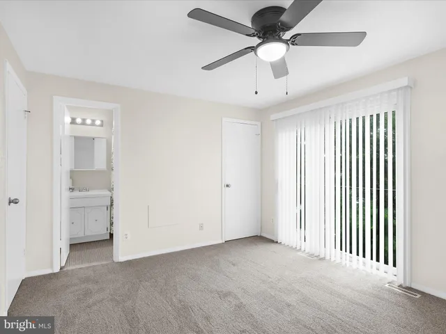 an empty room with chandelier fan and windows