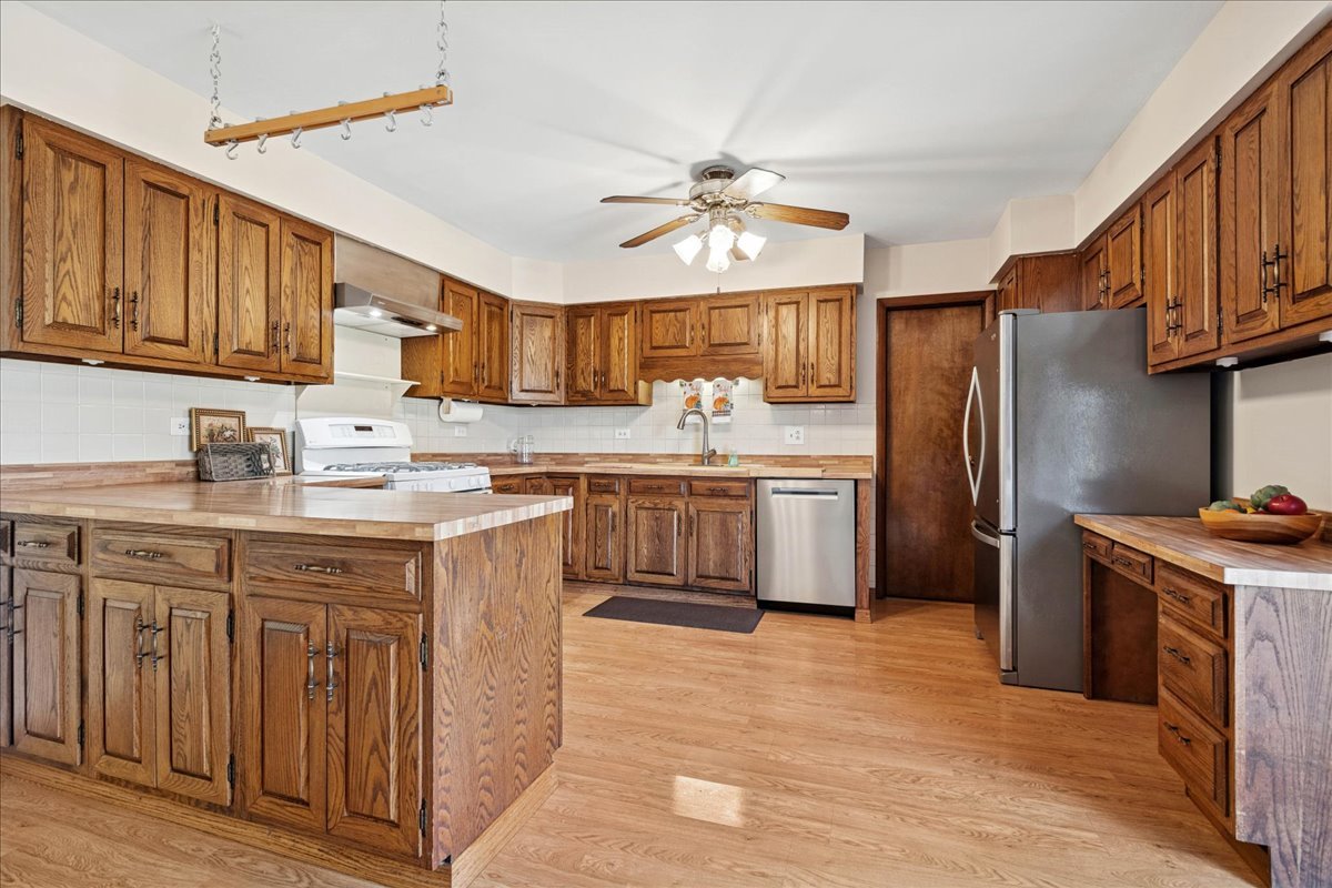 23565 North Park Road Lake Zurich, IL 60047 - Photo 5 of 26 a kitchen with stainless steel appliances granite countertop a refrigerator a sink dishwasher a stove with wooden cabinets and floor