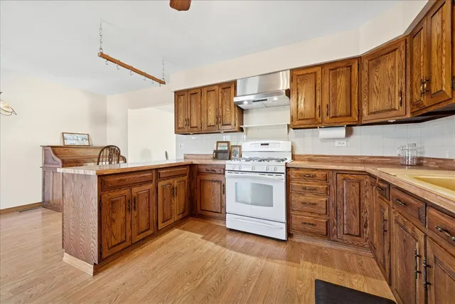 a kitchen with stainless steel appliances granite countertop a stove top oven a sink dishwasher and white cabinets with wooden floor