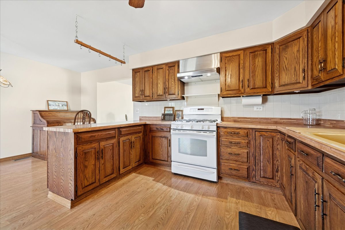 23565 North Park Road Lake Zurich, IL 60047 - Photo 6 of 26 a kitchen with stainless steel appliances granite countertop a stove top oven a sink dishwasher and white cabinets with wooden floor