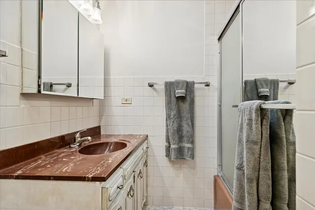 a bathroom with a granite countertop sink a mirror and shower