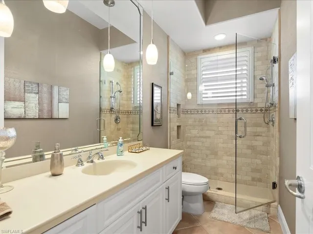 a bathroom with a granite countertop sink a toilet a mirror and shower