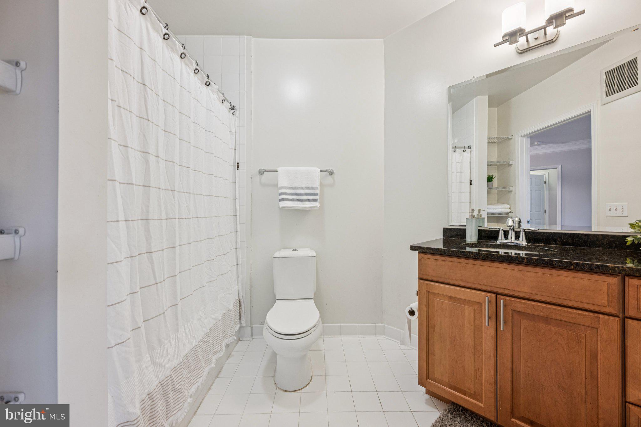 2101 North Monroe Street, Unit 107 Arlington, VA 22207 - Photo 23 of 24 a bathroom with a granite countertop toilet sink and mirror