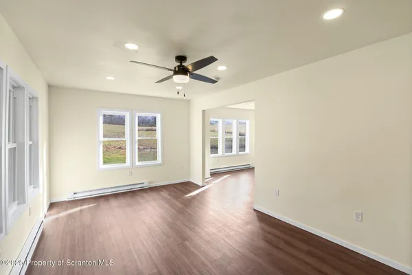 an empty room with wooden floor and windows