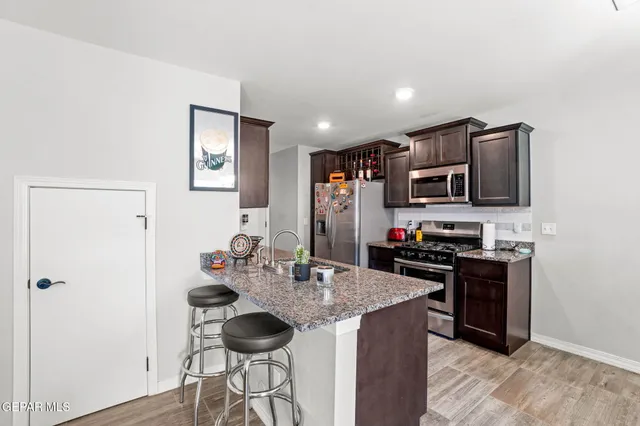 a kitchen with stainless steel appliances granite countertop a stove top oven a sink and a refrigerator