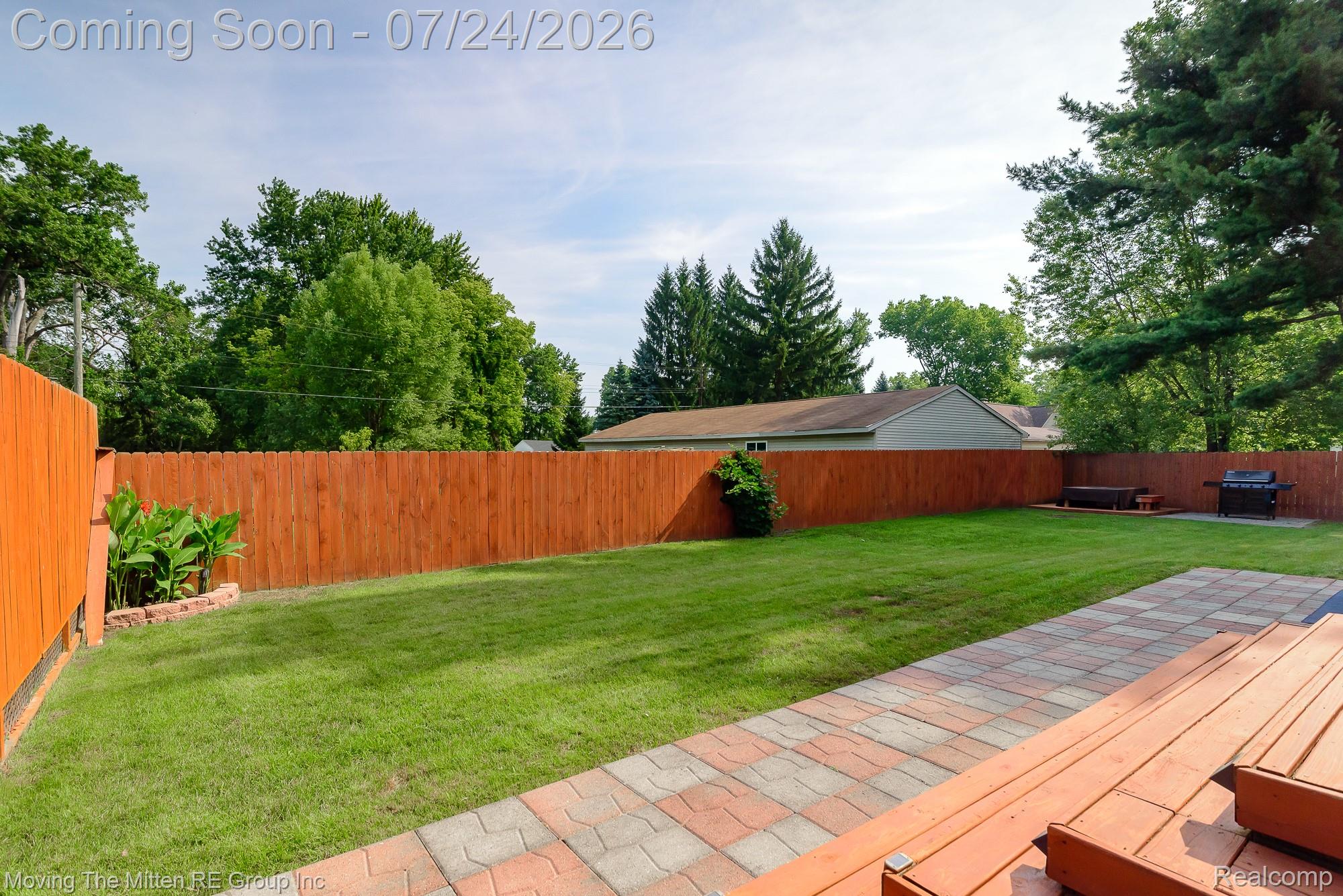 37460 Tyler Road Romulus, MI 48174 - Photo 42 of 52 Expansive backyard featuring a stained wood privacy fence, a manicured lawn, a paver patio, and mature perimeter trees