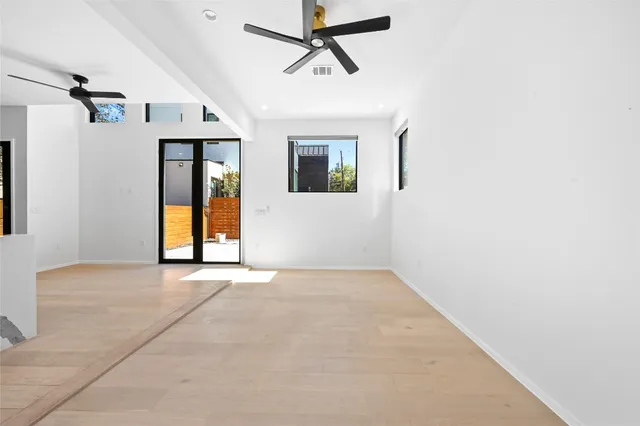 a view of an empty room with window and a ceiling fan