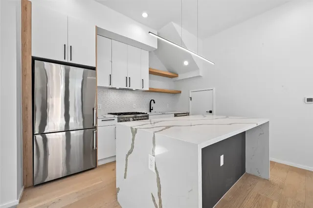 a kitchen with stainless steel appliances granite countertop a sink a stove and a refrigerator